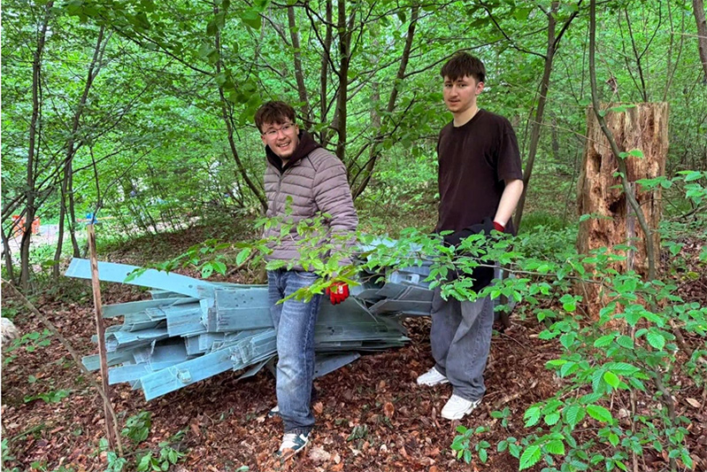 Zwei Schüler tragen entfernte Wuchshüllern aus dem Wald