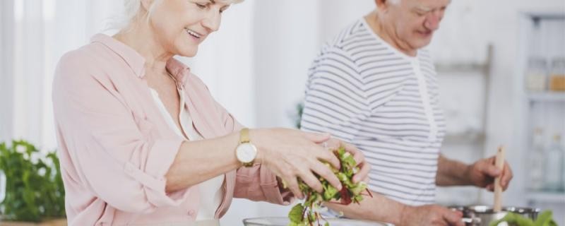 Senioren bereiten grünen Salat zu 