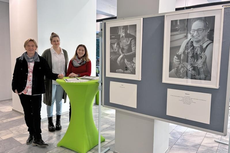 Gruppenbild Ein Gruppenbild mit 3 Personen an einem Stehtisch neben einer Stellwand mit 2 Porträt-Bildern