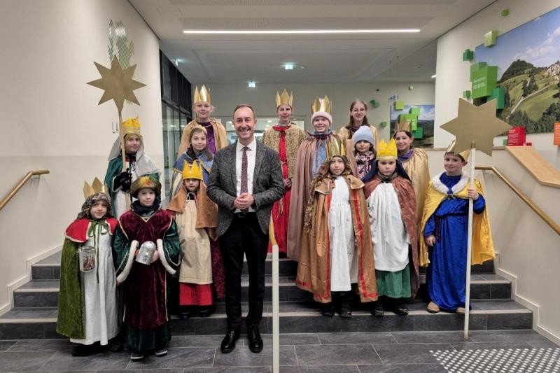Eine Gruppe von Kindern, kostümiert als Sternsinger, mit Landrat Markus Möller in der Mitte.