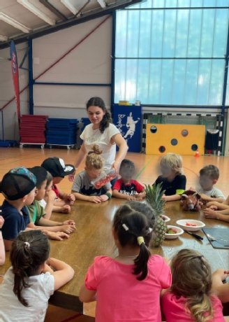 Kinder sitzen um einen Tisch und riechen an Obst 