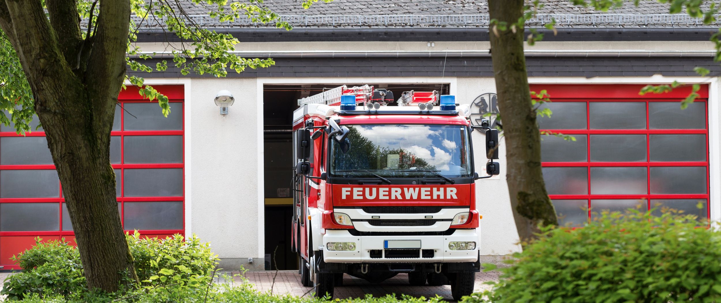 Feuerwehrauto Ein Feuerwehrauto fährt aus einer Fahrzeughalle