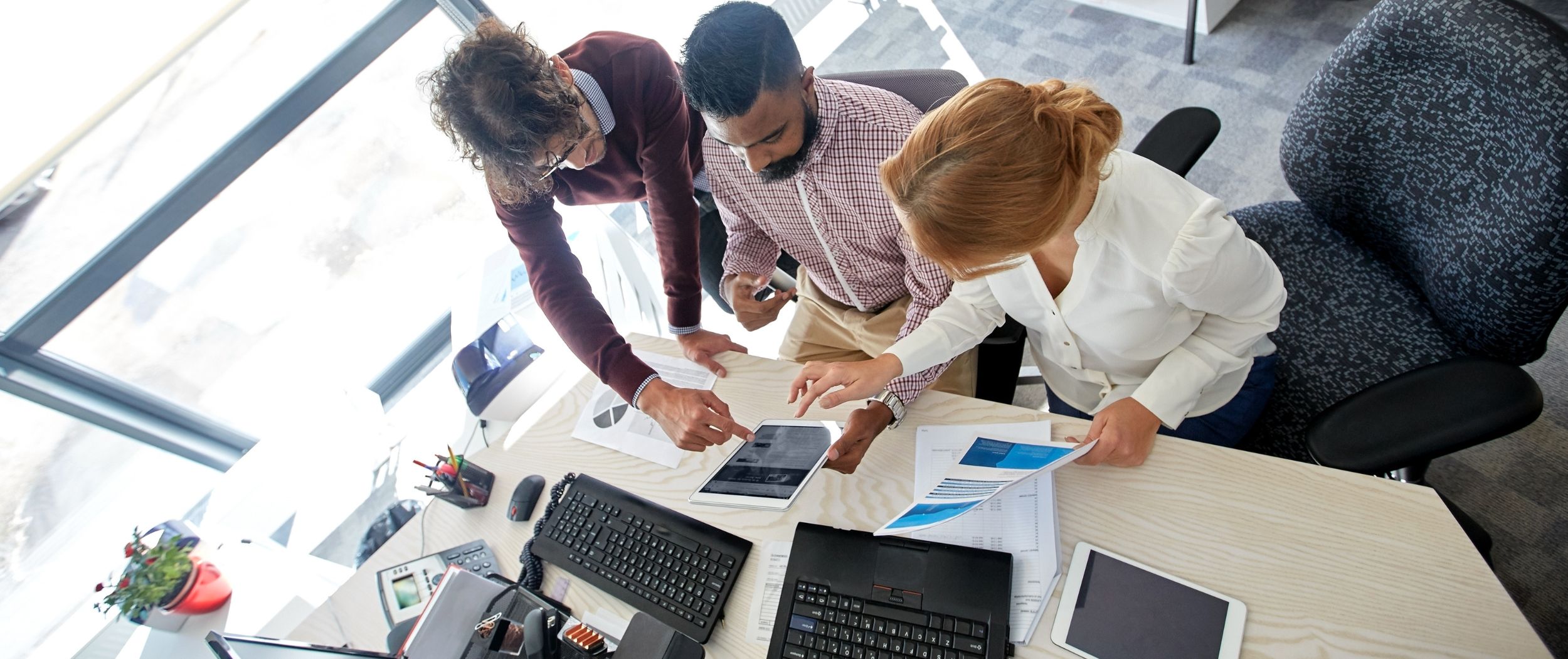Besprechung Drei Personen bei einer Besprechung an einem Schreibtisch