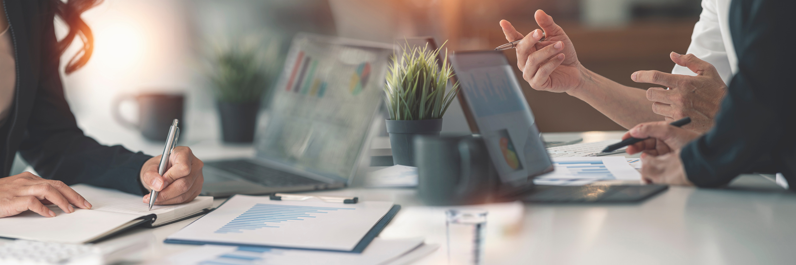 Mehrere Personen besprechen Statistiken mit Laptop und Tablet an einem Bürotisch