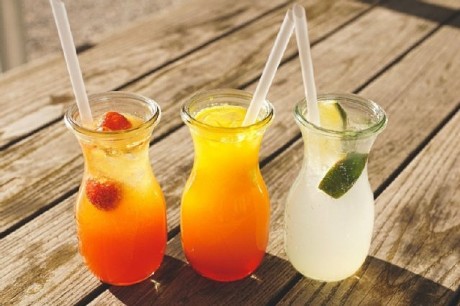 Sirup, Limonade und Co. Limonaden in Orange, gelb und weiß in Gläsern mit Strohhalm