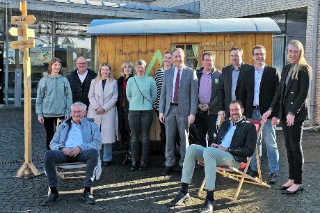 Menschen Stehen vor einem Gebäude und einem Schäferwagen.