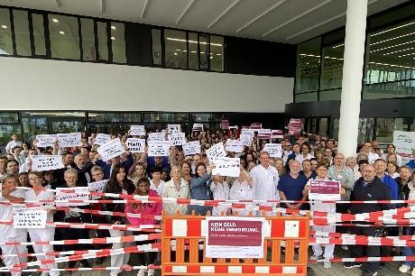 Mitarbeitende halten vor dem Klinik-Haupteingang Protestschilder hoch. Der Bereich ist symbolisch abgesperrt.