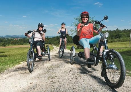 Drei Frauen auf den Drei- bzw. Fahrrädern fahrend auf dem Feldweg