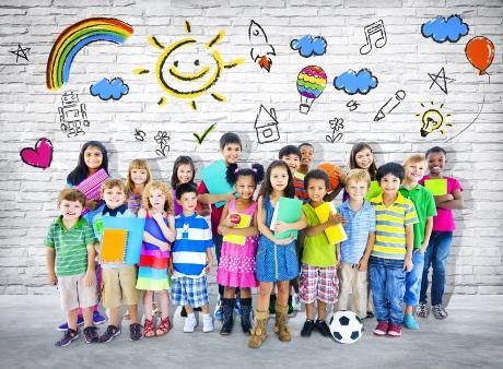 Eine Gruppe Kinder mit Schulsachen in der Hand stehen vor einer Mauer