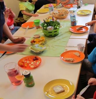 weißer Tisch mit bunten Tellern und Kindern die Essen