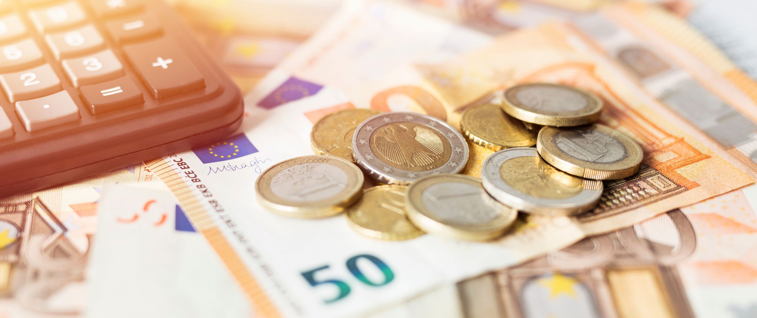 Münzen und Euroscheine Münzen, Euroscheine und ein Taschenrechner liegen auf einem Tisch